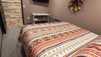 A bedroom with a bed, a television on the wall, a small table, and a decorative wall piece.
