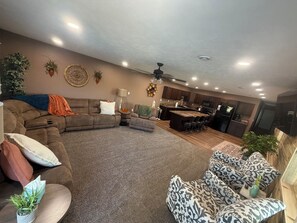 A modern living room with a sectional sofa, a coffee table, and a patterned armchair. - The Back 40 Hideaway Huron, SD 5BR Getaway (Huron)