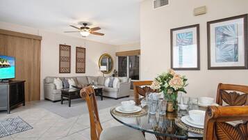 A living room with a sofa, a coffee table, and a dining table set for four.