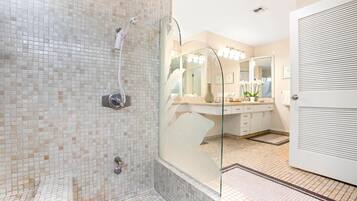 A modern bathroom with a glass-enclosed shower, a large mirror, and a vanity with a sink and countertop.