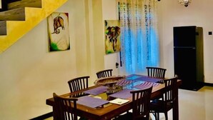 A dining area with a wooden table and chairs, a staircase, and a ceiling light fixture. - Asoria Luxe Villa & Retreat (Kegalle)