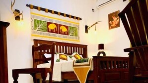 A room with a bed, a wooden chair, a small table, and a wall tapestry. - Asoria Luxe Villa & Retreat (Kegalle)