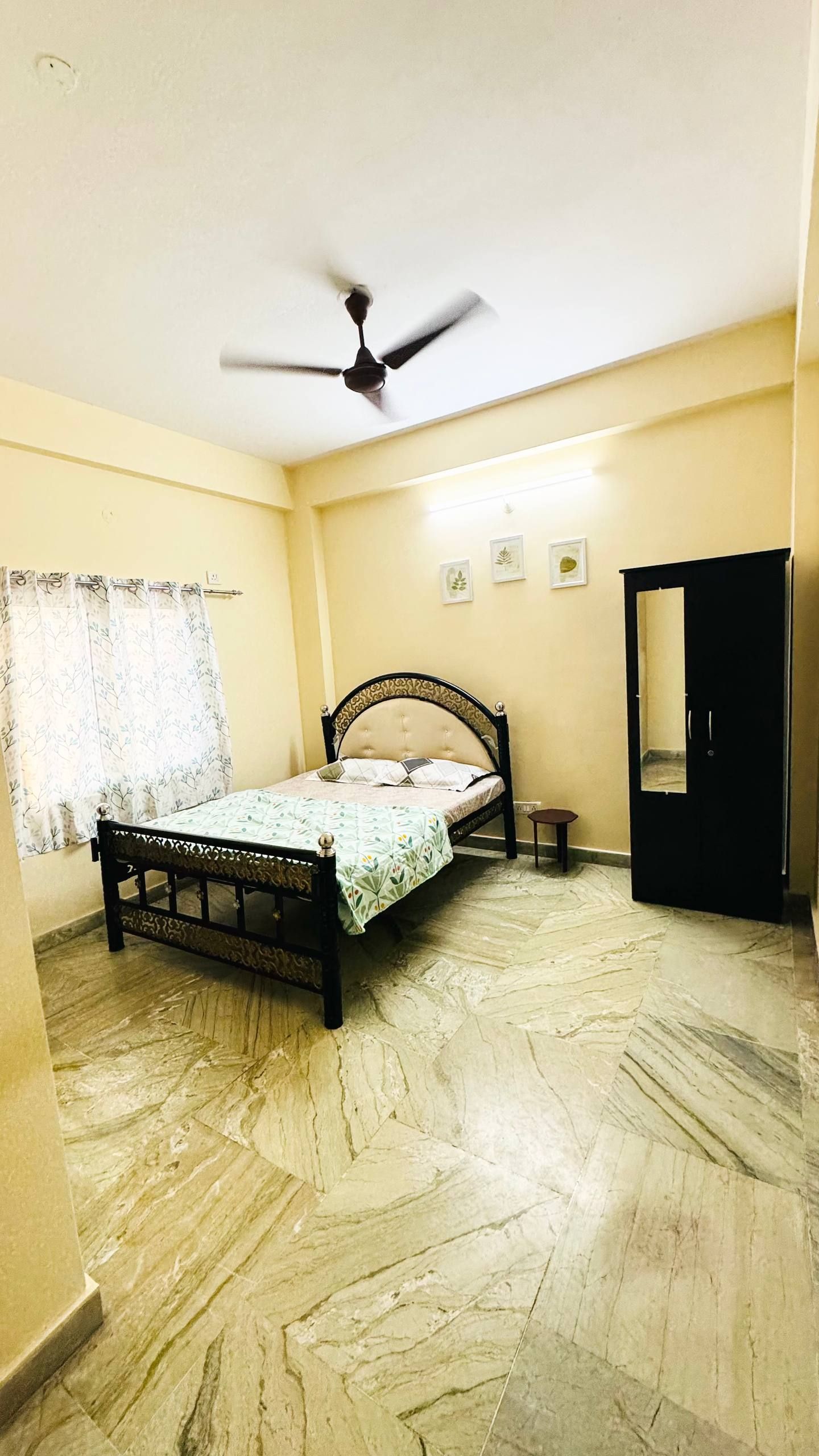 Un dormitorio con cama, ventilador de techo, armario y una mesita.