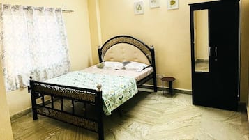 Un dormitorio con cama, ventilador de techo, armario y una mesita.