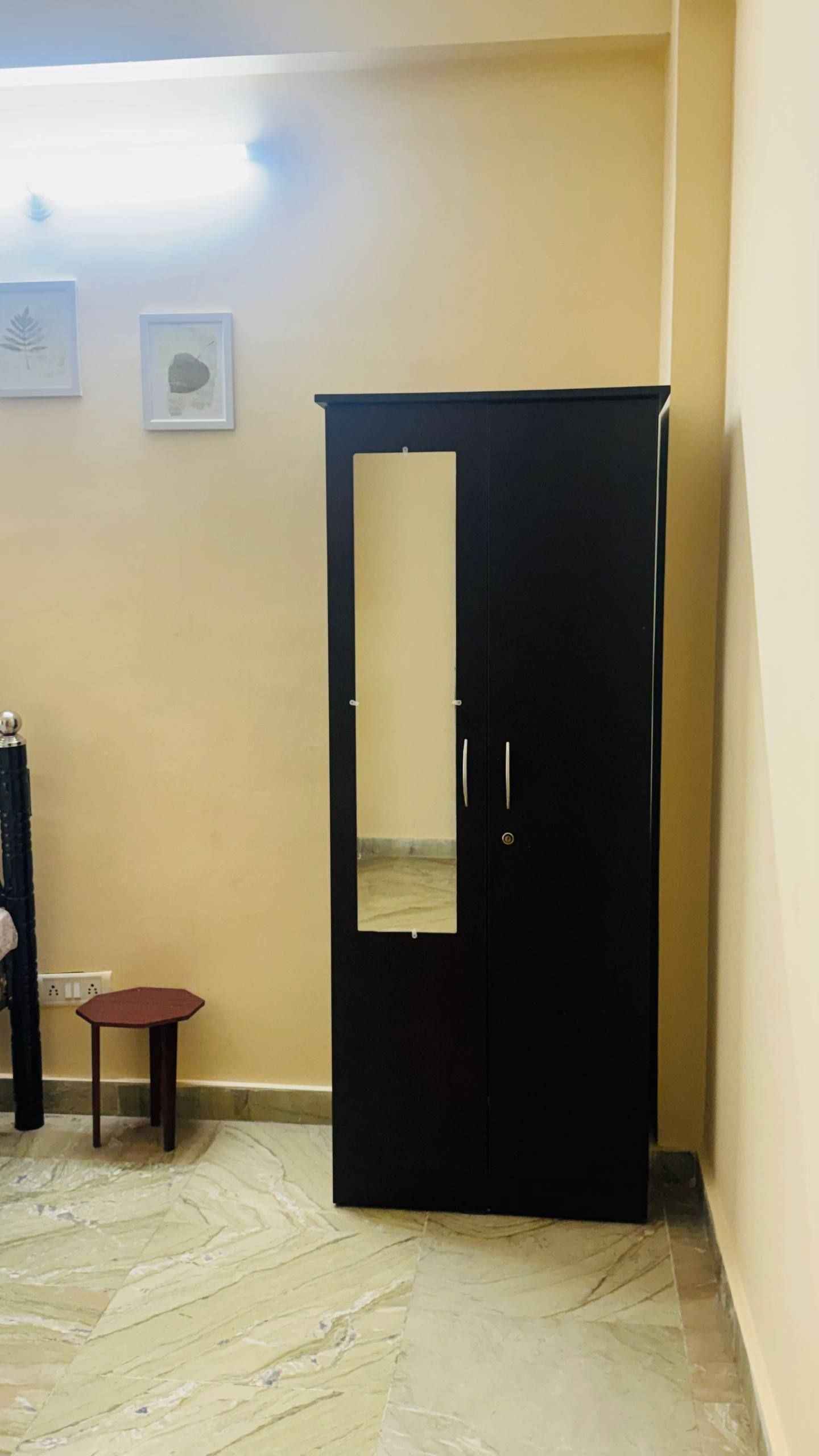 A room with a black wardrobe, a small wooden table, and a marble floor.