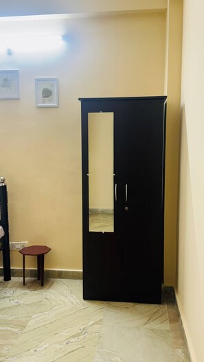 Una habitación con un armario negro, una mesita de madera y un suelo de mármol.