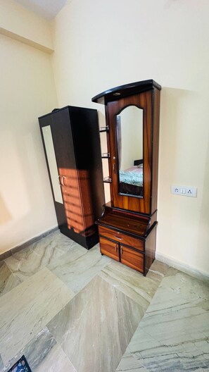 Una habitación con un armario de madera, un espejo y una cama con colcha estampada.