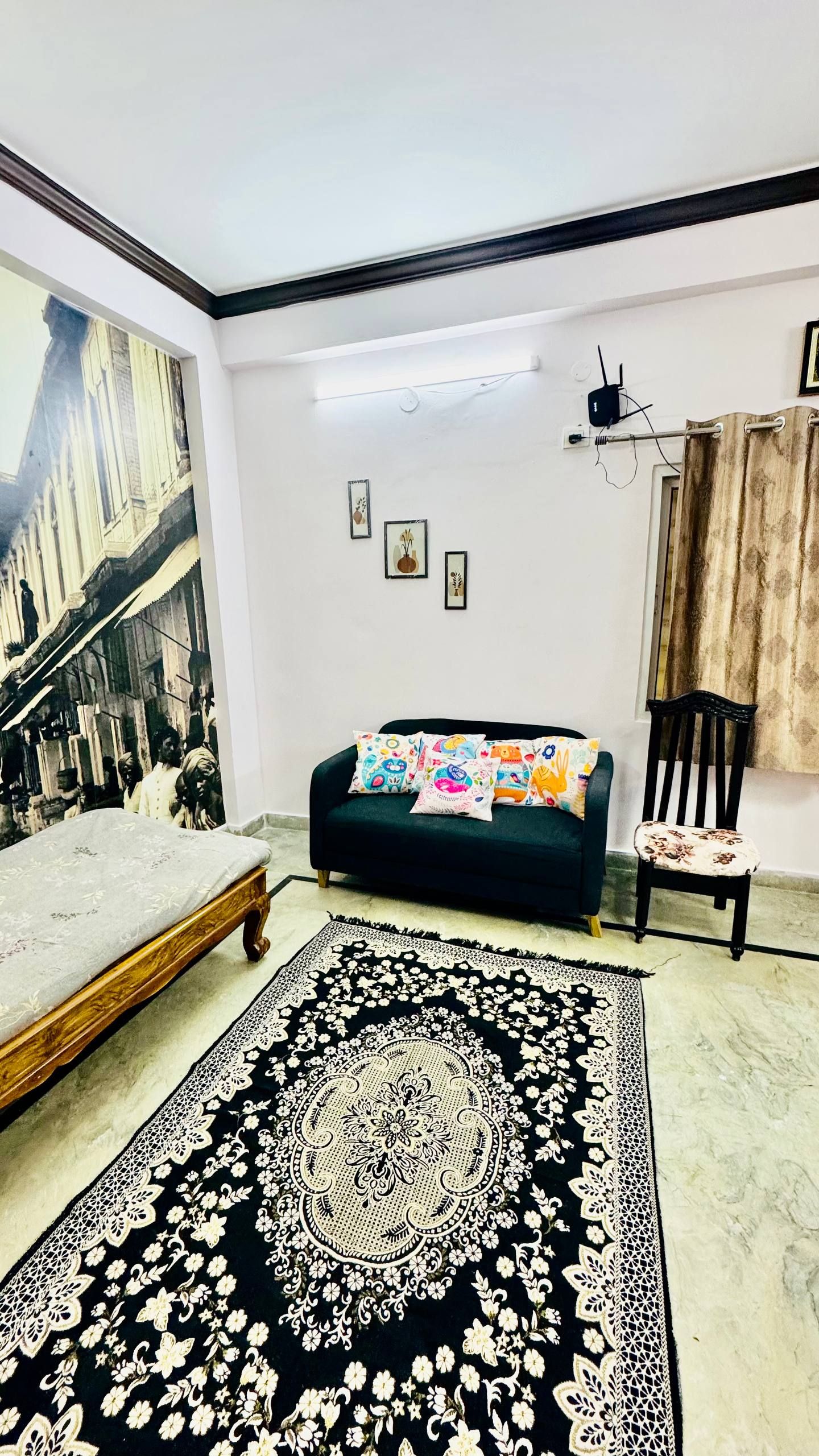 A living room with a sofa, a chair, a large painting, and a patterned rug.