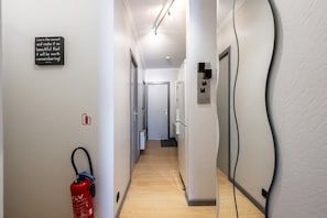 Ein Flur mit an der Wand montiertem Feuerlöscher, einem Schild mit einem Zitat und einer Tür mit Zahlenschloss.