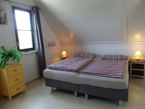 A bedroom with a bed, bedside lamps, a dresser, a window, and a plant. - Holiday Home With 2 Bedrooms (Callantsoog)