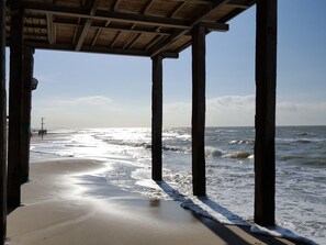 A beach view from a wooden structure with columns, leading to the ocean. - Holiday Home With 2 Bedrooms (Callantsoog)