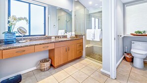 Een moderne badkamer met een grote spiegel, een aanrechtblad van graniet, houten kastjes en een douchecabine van glas.