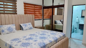 A bedroom with a bed, a nightstand, a mirror, and a bathroom visible through an open door. - Santa Capuza 2 (Sánchez  las garitas)