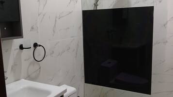 Casa de banho com sanita, lavatório e zona de duche.
