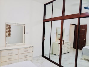 A bedroom with a bed, a dresser, a mirror, and a wardrobe.