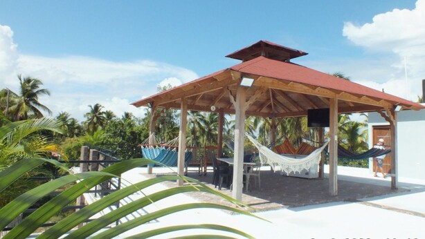 A wooden gazebo with a red roof, surrounded by palm trees and a clear sky. - Santa Capuza 2 (Sánchez  las garitas)