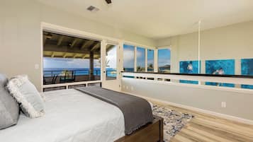 Un dormitorio con cama, vista al océano y obras de arte en la pared.