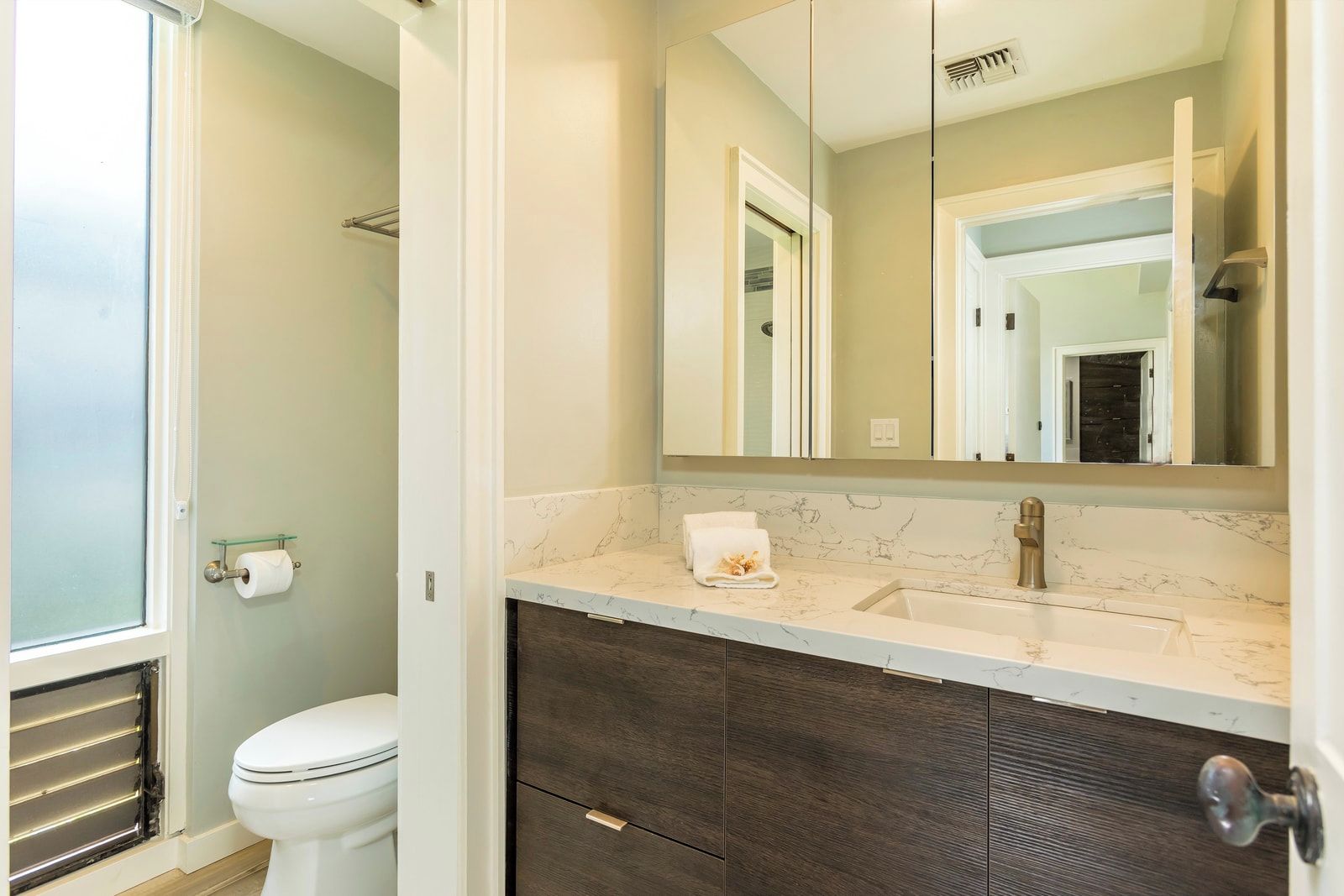 Une salle de bain avec des toilettes, un lavabo, un miroir et une serviette posée sur le comptoir.