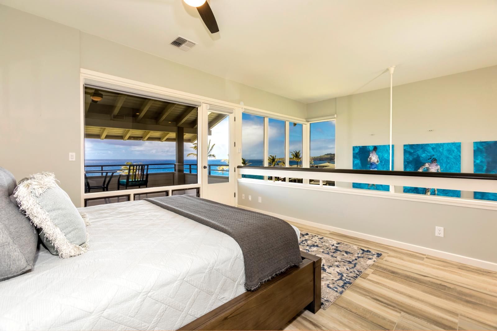 Een slaapkamer met een groot bed, uitzicht op zee en kunst aan de muur.