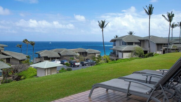 A coastal residential area with houses, a grassy lawn, and a view of the ocean. - Kapalua Bay Villas | 3 Oceanfront Villas, Sleeps 16 | Car Incl. w/ 6+ Nights | ML-4709 by KBM (Lahaina)