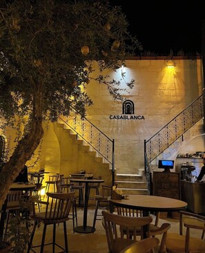 Un espace extérieur aménagé avec des tables et des chaises, un escalier menant à un niveau supérieur et un mur orné de l’inscription « CASABLANCA ».