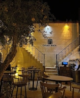 Un área de estar al aire libre con mesas y sillas, una escalera que conduce a un nivel superior y una pared con el letrero 'CASABLANCA'.