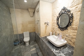 Casa de banho com lavatório de mármore, sanita e espelho com moldura ornamentada.