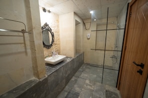 A bathroom with a sink, mirror, shower, and a wooden door. - Casa Blanca otel (Şanlıurfa)