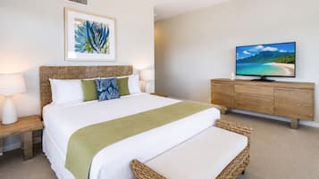 Una habitación de hotel con una cama, un televisor, un cuadro enmarcado y una mesita de noche de madera.