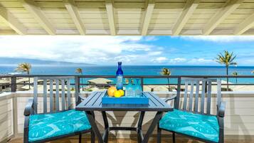 Un balcon avec une table, des chaises et une vue sur l’océan.
