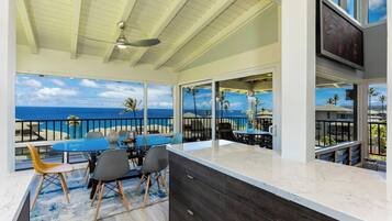 A modern kitchen with a large island, a dining area with a view of the ocean, and a ceiling fan.