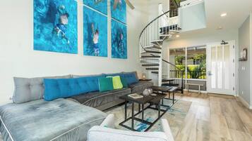 A modern living room with a sectional sofa, a coffee table, and a staircase leading to an upper level.