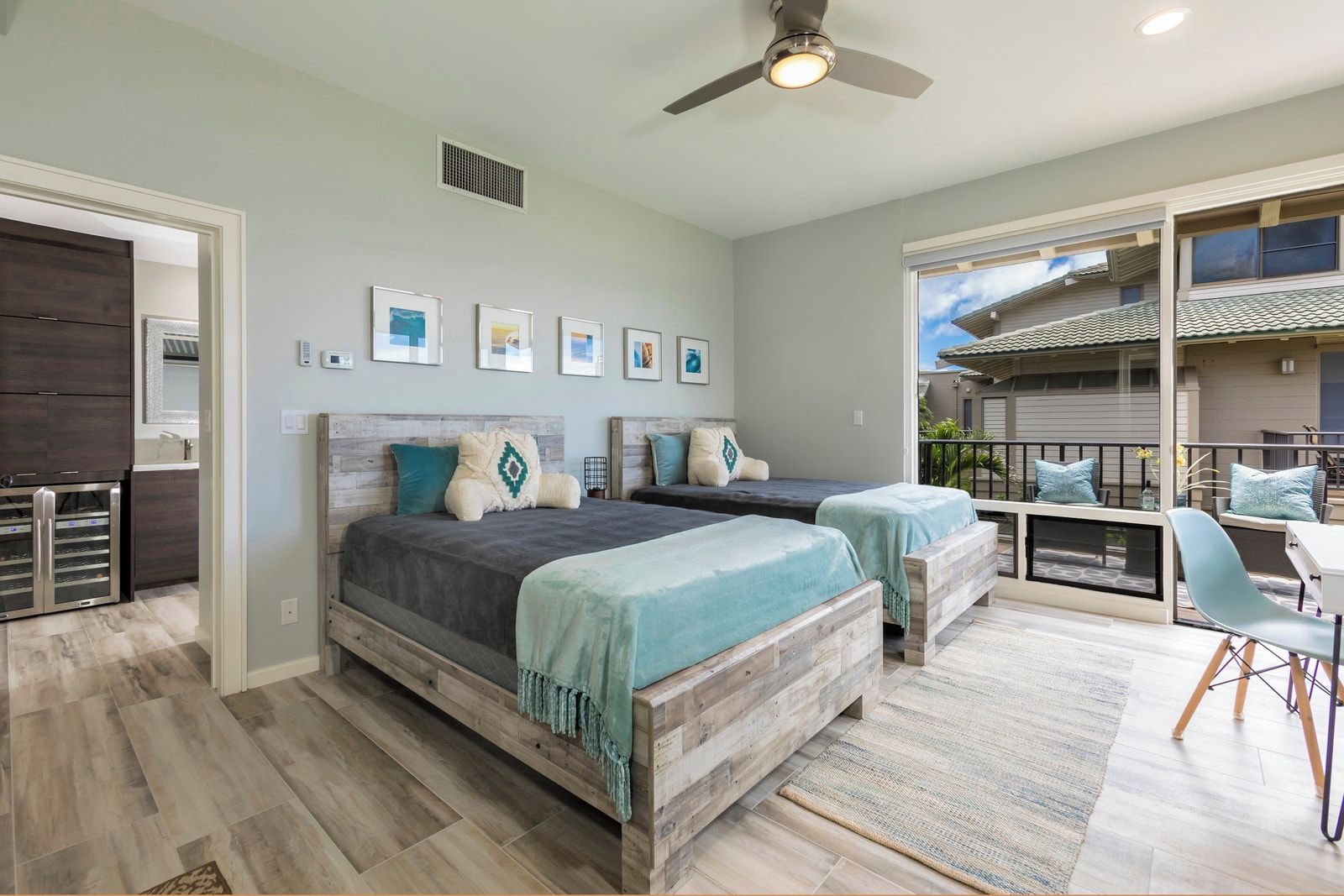 A bedroom with two beds, a ceiling fan, and a view of the outside.