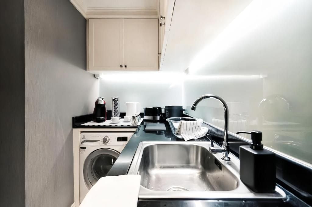 A compact kitchen with a washing machine, a sink, and a countertop with various appliances.