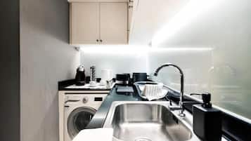 A compact kitchen with a washing machine, a sink, and a countertop with various appliances.