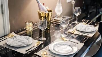 A dining table set with plates, cutlery, and glasses, with a bottle of champagne in a gold bucket.