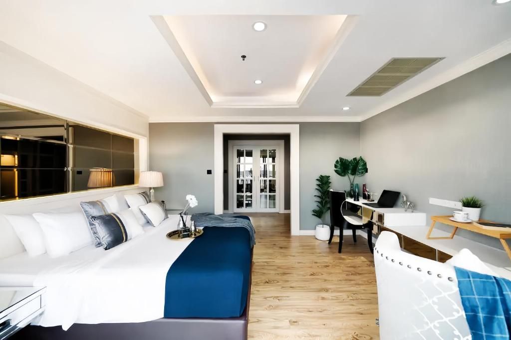 A modern hotel room with a large bed, a desk, and a seating area.