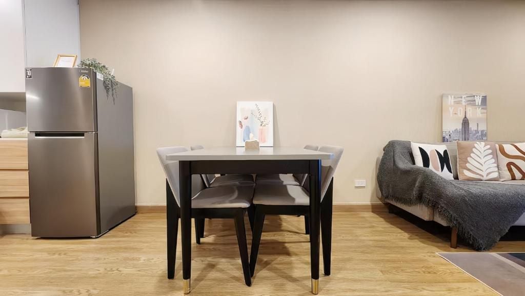 A compact living space with a kitchenette, a dining table with chairs, a sofa, and a small rug.