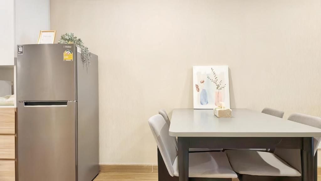 Una cocina moderna con un refrigerador de acero inoxidable, una mesa de comedor con sillas y una obra de arte enmarcada en la pared.
