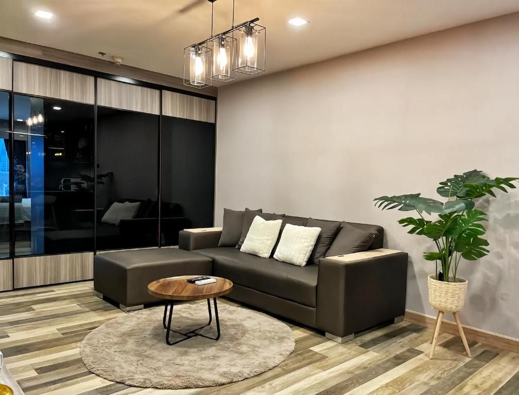 A modern living room with a sectional sofa, a round coffee table, and a potted plant.