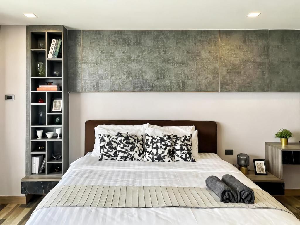 Un dormitorio moderno con cama, estantería empotrada, pared texturizada grande y mesita de noche con lámpara.