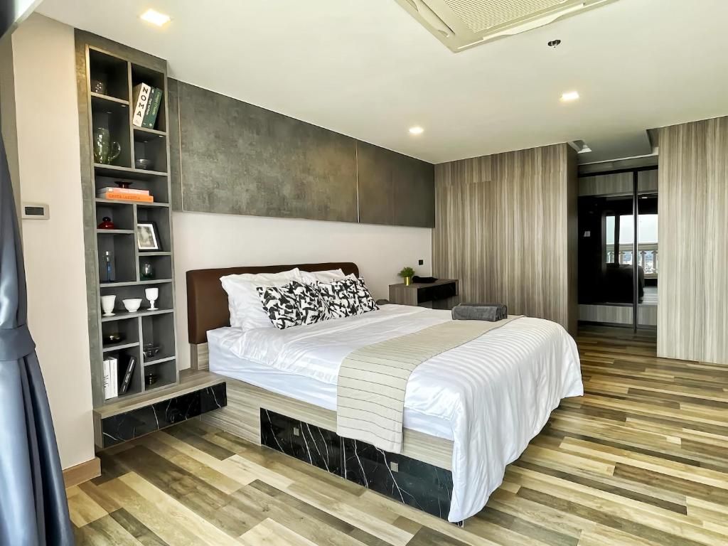 A modern bedroom with a large bed, a built-in bookshelf, and a view of the city.