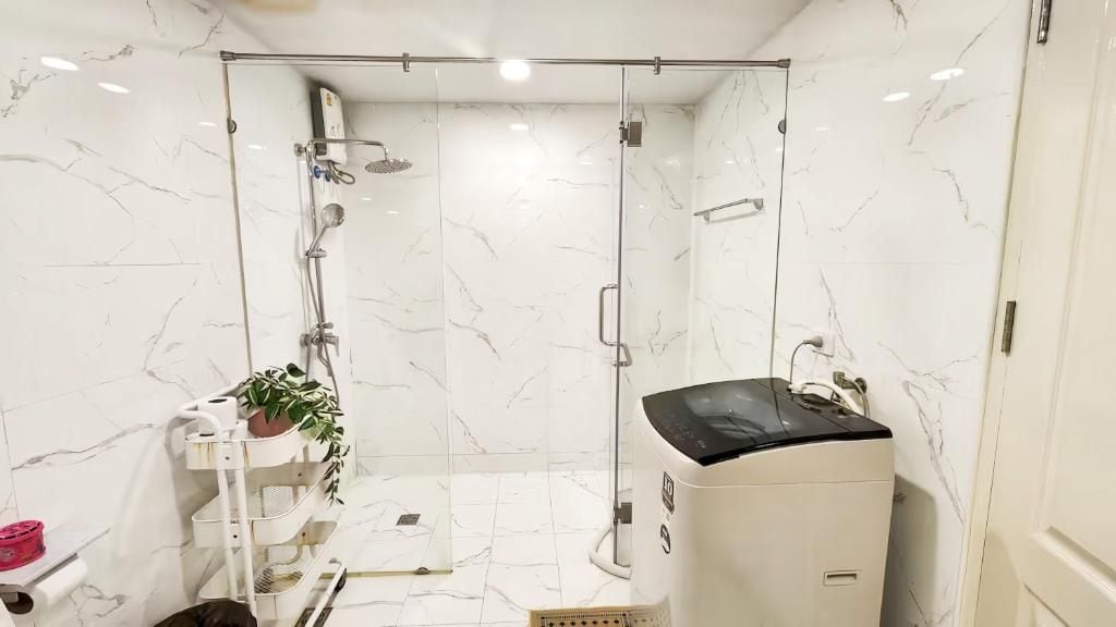 A bathroom with a glass-enclosed shower, a white marble wall, and a white pedestal sink.