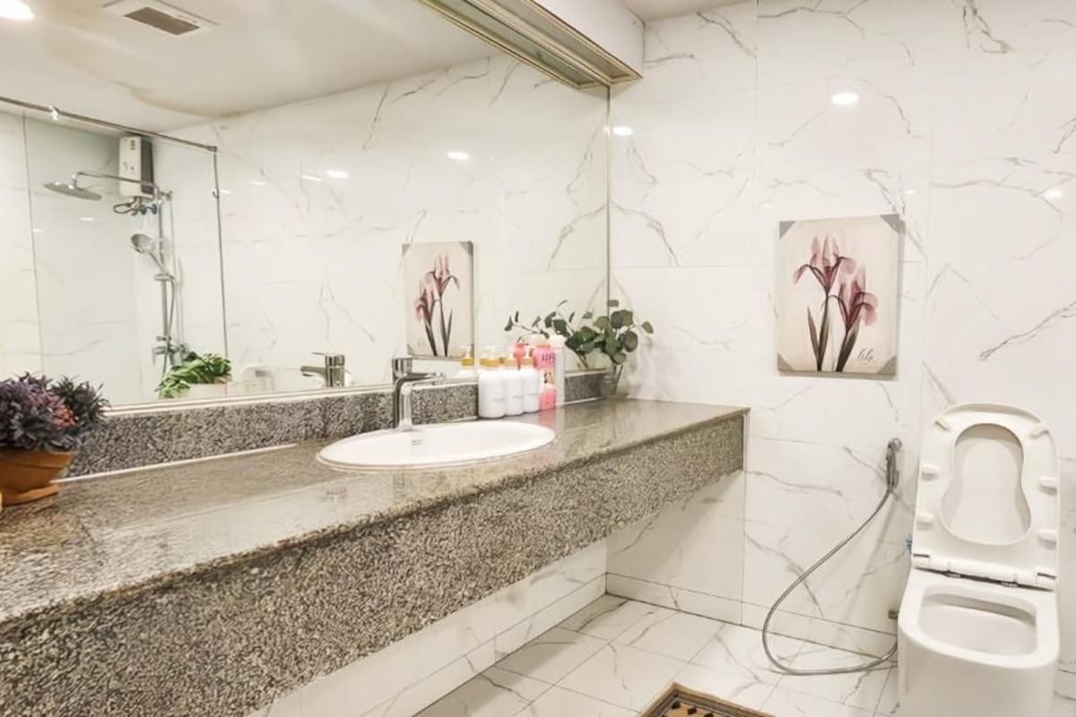 Un baño con lavamanos de mármol, ducha e inodoro.