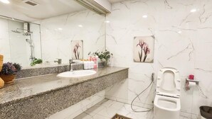 A bathroom with a marble sink, a shower, and a toilet. - State Tower Bangkok (Krung Thep Maha Nakhon)