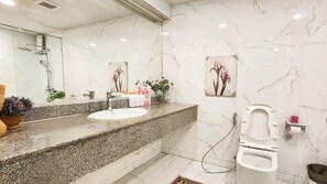 Un baño con lavamanos de mármol, ducha e inodoro.