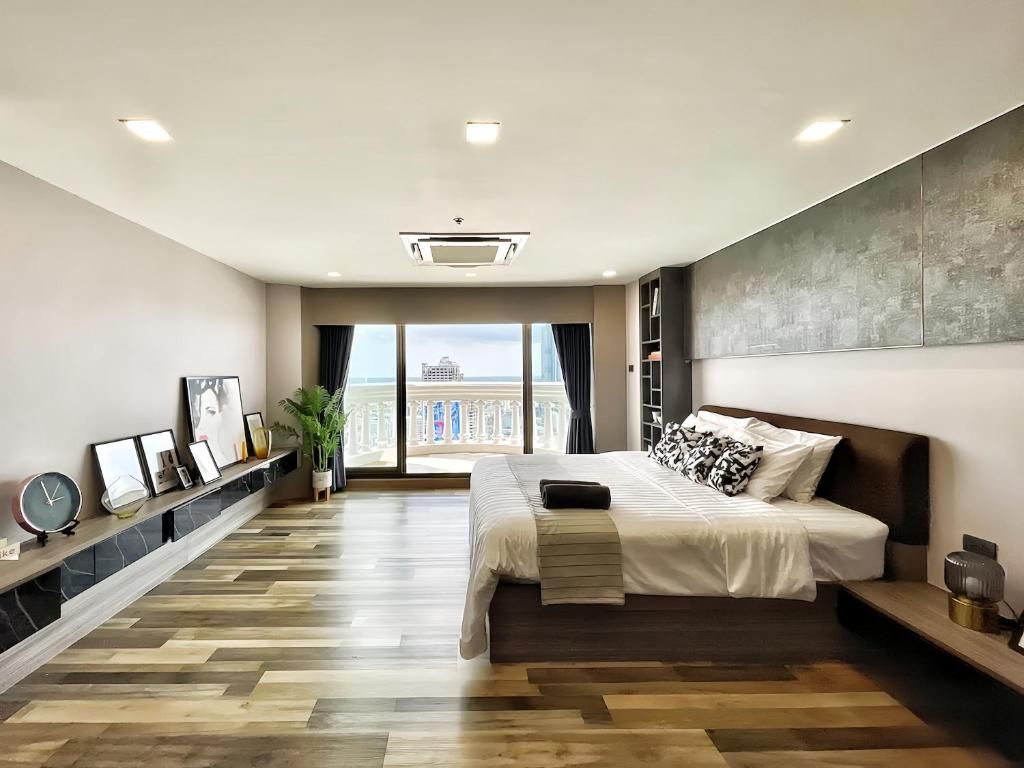 A modern bedroom with a large bed, a view of the city, and a wooden floor.