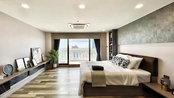 A modern bedroom with a large bed, a view of the city, and a wooden floor.
