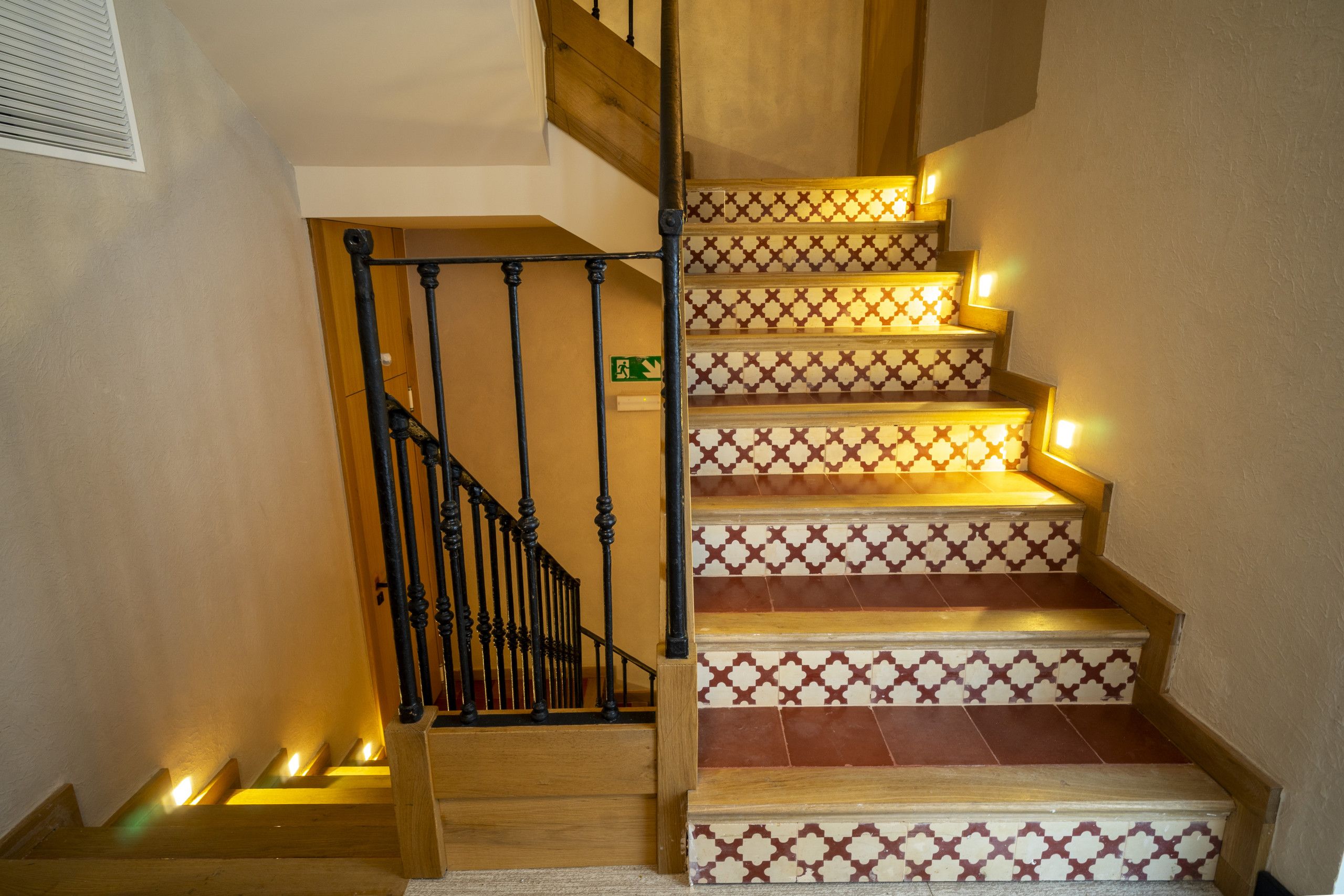A staircase with a wooden handrail and patterned steps, leading to an upper floor.
