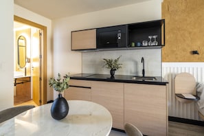 Una cocina moderna con un microondas negro, un lavamanos y un comedor con una mesa redonda y un florero.